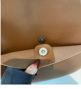 Close-up of premium metallic magnetic clasp and suede texture on a brown tote bag