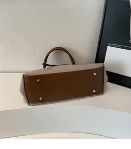 Detail view of the bag base featuring protective silver metal studs and brown leather