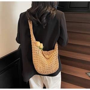Detail of hand-woven hollow knit crossbody bag with wooden button and tulip accent
