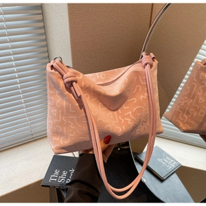 Détail du sac sous l'aisselle en cuir rose gaufré avec doubles bandoulières nouées et zip argent