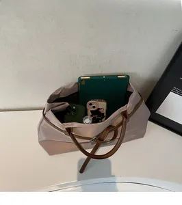 Top view showing large interior storage of the champagne nylon tote with gadgets