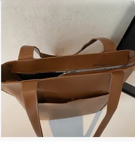 Close-up of the smooth top zipper closure on the large brown leather tote bag