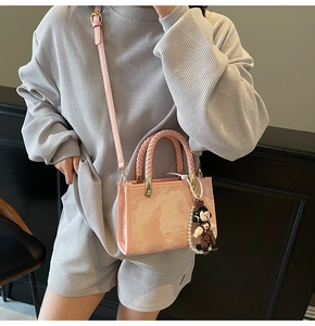 Chic pink marble print square bag shown on model with woven handle and cute plush charm