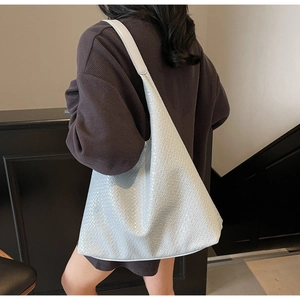 Side view of large crocodile pattern hobo bag worn by model in light blue finish