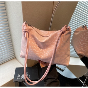 Détail d'un sac cabas en cuir rose avec motif géométrique gaufré et bandoulière à nœud
