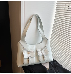 Detail of multi-pocket commuter tote bag with metal heart charms and buckle straps