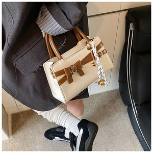 Detail einer schicken beige-braunen Umhängetasche mit Schleife und Quastenanhänger