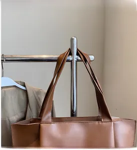 Detail of sturdy brown leather tote handles and clean stitching on a professional commuter bag