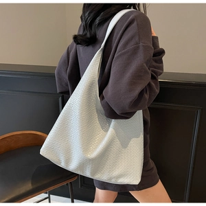 Close-up of white embossed leather tote bag with wide shoulder strap and large capacity