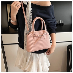 Detailansicht der rosa Handtasche mit vertikaler Plissee-Textur und runden Tragegriffen