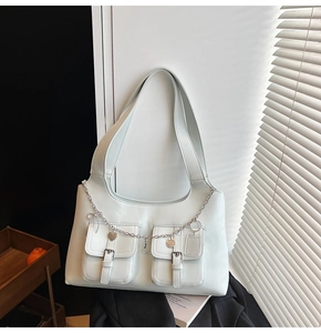 Detail of light blue faux leather tote bag with silver chain, heart charm and buckles
