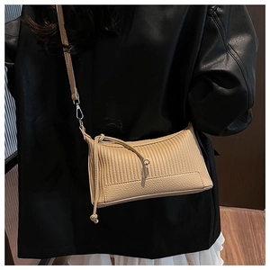 Détail du sac beige montrant la texture plissée et le contraste du grain de litchi