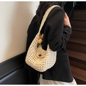 Detail shot of cream crochet shoulder bag featuring hollow knit patterns and a dark button