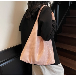 Detail of pink woven leather hobo bag showing intricate texture on female shoulder