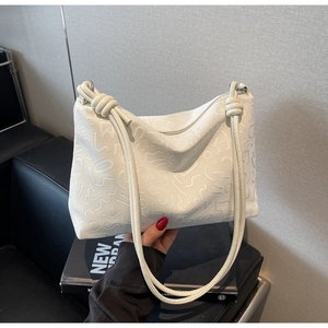Détail du cabas en cuir blanc présentant des textures gaufrées et des lanières nouées