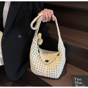 Detail of cream handmade hollow crochet bucket bag with diamond grid and button closure