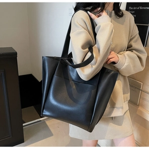 Detailed view of black large capacity tote bag with front pocket on a shoulder