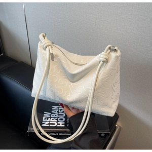 Détail du sac cabas crème avec motifs géométriques en relief et fines bandoulières nouées