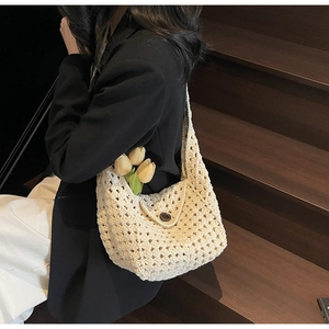 Detail of hand-woven hollow knit bag with a round button closure and floral accent