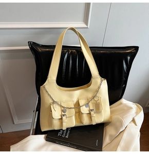 Detail of a light yellow PU leather tote bag with functional pockets and heart pendant chain