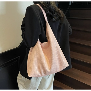 Detailed back view of a pink woven tote bag worn with a black blazer for work