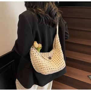 Detail of hand-woven beige crochet shoulder bag showing hollow texture and round buckle