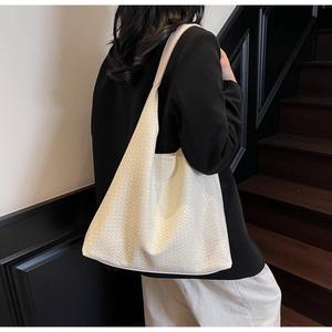 Close-up of cream woven leather tote bag texture on a shoulder hobo bag design