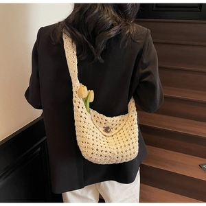 Detailed macro view of cream crochet knit bag featuring hollow texture and wooden button closure