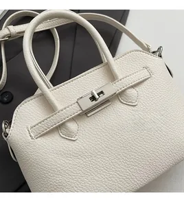 Dettaglio ravvicinato di una borsa in pelle martellata crema con chiusura girevole in metallo
