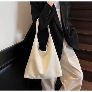 Detailed view of beige woven tote bag texture with smooth leather shoulder strap detail