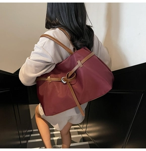 Deep burgundy nylon tote bag with brown leather straps worn on the shoulder in a staircase