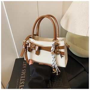 Detailansicht der kleinen Retro-Handtasche in Weiß mit brauner Schleife und gestreiftem Seidenschal