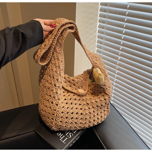 Close-up of khaki crochet knit shoulder bag featuring hollow weave and wooden button