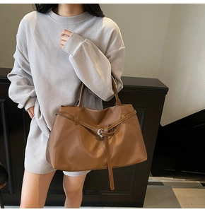 Detailed view of a brown tote bag featuring silver round buckles and textured faux leather