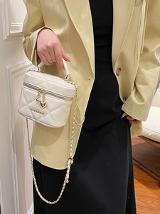 Sac cylindre matelassé beige chic avec chaîne dorée et breloques cœur pour le style
