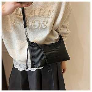 Détail d'un sac à bandoulière plissé noir avec texture verticale et décoration à cordon long