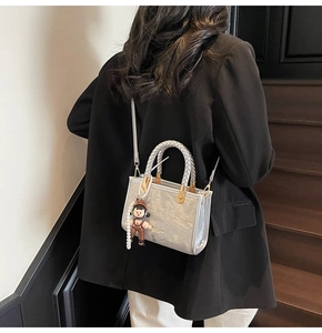 Detail of silver metallic square handbag with cute cartoon charm and textured finish