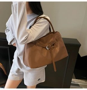 Detail of large brown soft leather tote bag featuring a decorative ring knot design