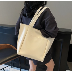 Detailed view of beige tote bag featuring a front pocket and soft textured synthetic leather