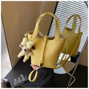Bright yellow pebbled leather bucket bag with metal padlock and cute puppy charm detail