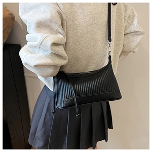 Détail d'un sac bandoulière noir plissé avec fermeture éclair argentée porté par un mannequin