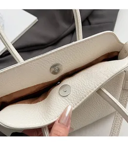 Dettaglio della chiusura magnetica di una borsa in pelle beige con fodera interna marrone