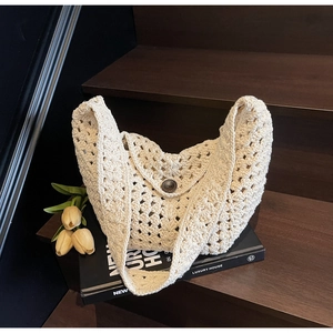 Detailed close-up of cream knit crochet bag featuring hollow pattern and round wooden button