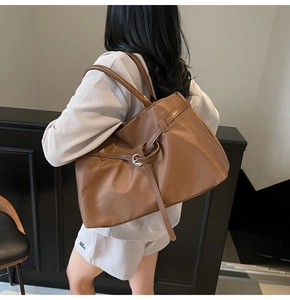 Detail of caramel brown tote bag with decorative ties and silver rings in a daily setting