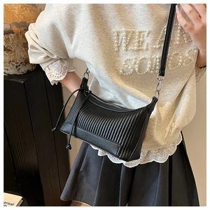 Gros plan sur le grain de cuir noir et les détails du zip argenté du sac à bandoulière
