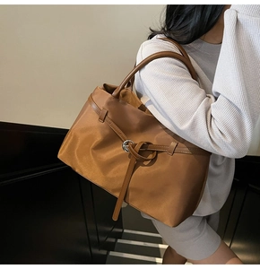 Close-up of brown large tote bag with shiny nylon fabric and retro buckle detail