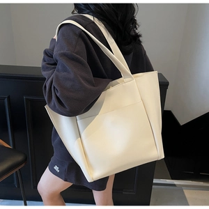 Minimalist creamy white faux leather tote bag shown on model for shoulder carry style
