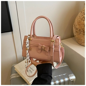 Detail der rosa glänzenden Handtasche mit Schleife und gestreiftem Seidenschal-Accessoire