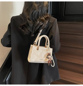 Detail of marble pattern handbag with braided handle, gold hardware and pearl chain