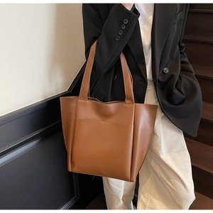 Brown leather tote bag featuring a practical front slip pocket and long shoulder straps
